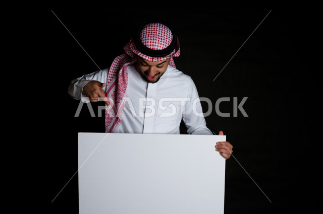 بورتريه لرجل سعودي خليجي سعيد بإيماءات الوجه المختلفة ، تعابير وجه و يدين مختلفة , يمسك بيده لوحة بيضاء ، خلفية سوداء