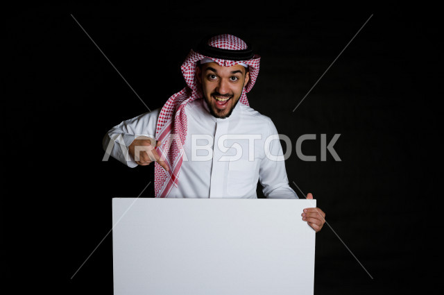 بورتريه لرجل سعودي خليجي سعيد بإيماءات الوجه المختلفة ، تعابير وجه و يدين مختلفة , يمسك بيده لوحة بيضاء ، خلفية سوداء