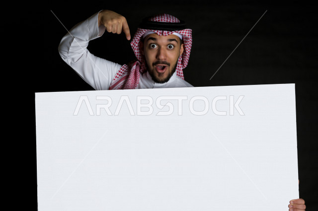 بورتريه لرجل سعودي خليجي سعيد بإيماءات الوجه المختلفة ، تعابير وجه و يدين مختلفة , يمسك بيده لوحة بيضاء ، خلفية سوداء