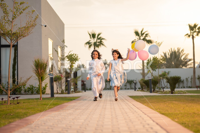 فرحة وبهجة الأطفال بقدوم العيد, الاستمتاع مع الأخوات بإيماءات البشاشة والسرور, أعياد ومناسبات اسلامية سعيدة,  ولد وفتاة عربيان خليجيان سعوديان يقومان بالركض في إحدى الشاليهات والمنتجعات السياحية, لحظات ممتعه مليئة بتعابير الفرح
