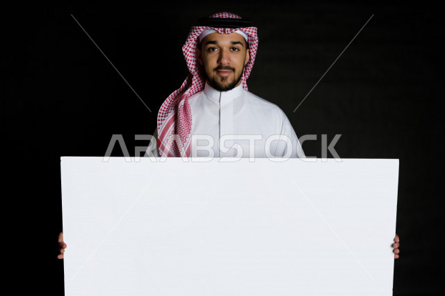 بورتريه لرجل سعودي خليجي سعيد بإيماءات الوجه المختلفة ، تعابير وجه و يدين مختلفة , يمسك بيده لوحة بيضاء ، خلفية سوداء