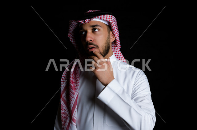 Portrait of a Saudi Gulf man with facial gestures indicating thinking and focus,black background