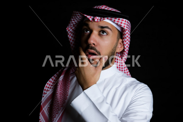 بورتريه لرجل سعودي خليجي بإيماءات الوجه تدل على التفكير و التركيز، خلفية سوداء