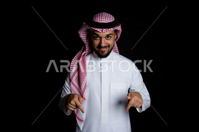 بورتريه لرجل سعودي خليجي سعيد بإيماءات الوجه المختلفة ، تعابير وجه و يدين مختلفة , يشير أصابعه إلى الأسفل ، خلفية سوداء 