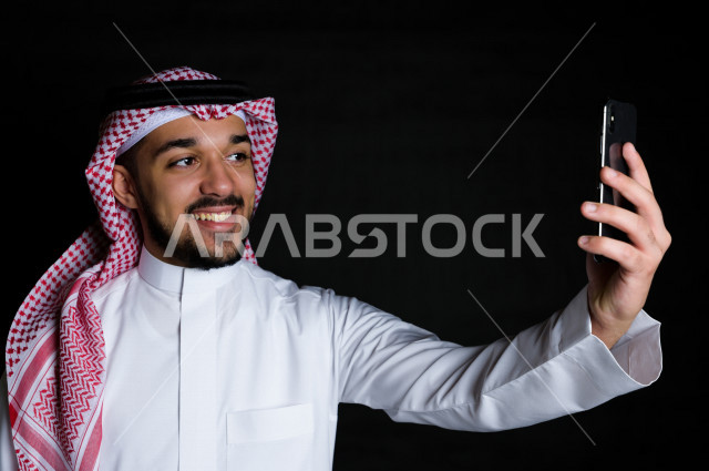 بورتريه لرجل سعودي خليجي يلتقط سيلفي  , خلفية سوداء  