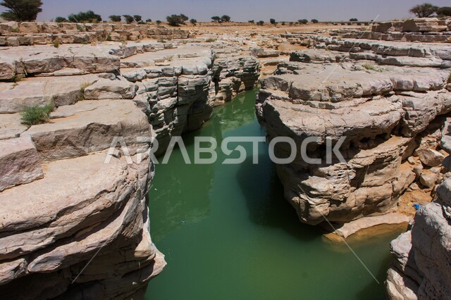 جريان المياه بين اخاديد الجبال في الوادي المخفي في محمية شرعان، الطبيعة الجبلية في محافظة العلا، المناظر الطبيعية المتميزة، التكوينات والتشكيلات الصخرية، المعالم السياحية التاريخية القديمة في المملكة العربية السعودية