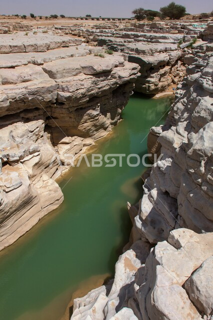 جريان المياه بين اخاديد الجبال في الوادي المخفي في محمية شرعان، الطبيعة الجبلية في محافظة العلا، المناظر الطبيعية المتميزة، التكوينات والتشكيلات الصخرية، المعالم السياحية التاريخية القديمة في المملكة العربية السعودية