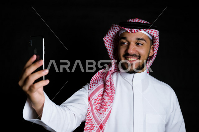 بورتريه لرجل سعودي خليجي يلتقط سيلفي  , خلفية سوداء  