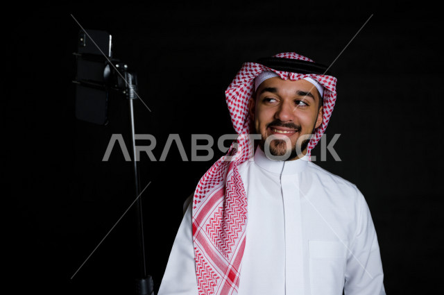 بورتريه لرجل سعودي خليجي يلتقط سيلفي  , خلفية سوداء  