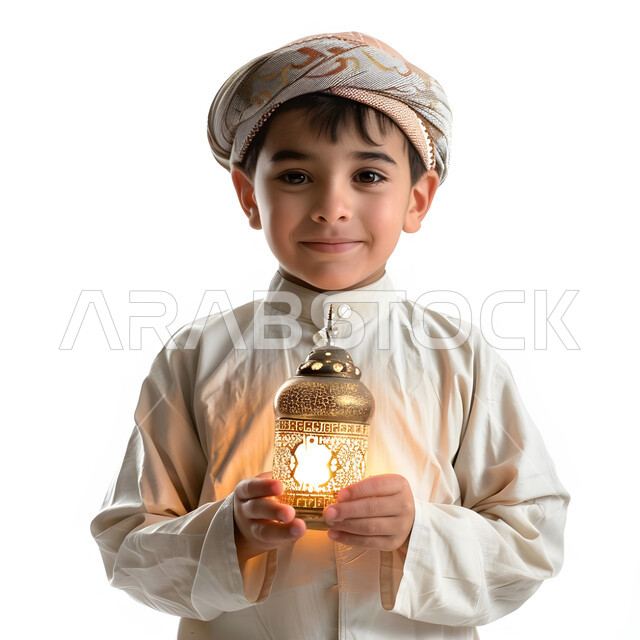تحف وزينة الاحتفالات في السعودية, استقبال شهر الخير والبركة, المناسبات الدينية والأعياد الإسلامية, الاستعداد لقدوم شهر رمضان, بورتريه مقرب  لولد عربي خليجي سعودي يرتدي الثوب و العمامة التقليدية يحمل الفانوس المضيء وينظر الى الكاميرا بتعابير الفرح, خلفية بيضاء