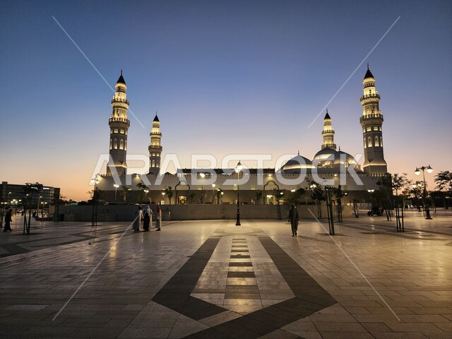 الساحة الخارجية لمسجد قباء في المدينة المنورة وقت الغروب، دعوة المسلمين لآداء الصلاة والتقرب إلى الله تعالى، معالم وأماكن دينية مقدسة في المملكة العربية السعودية، المآذن و القبب المضيئة، الفن الهندسي المعماري والديكورات الاسلامية على الطراز الحديث