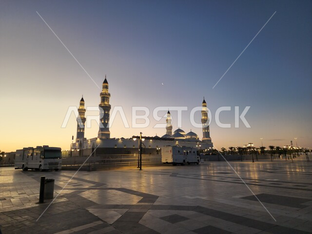 الساحة الخارجية لمسجد قباء في المدينة المنورة وقت الغروب، دعوة المسلمين لآداء الصلاة والتقرب إلى الله تعالى، معالم وأماكن دينية مقدسة في المملكة العربية السعودية، المآذن و القبب المضيئة، الفن الهندسي المعماري والديكورات الاسلامية على الطراز الحديث