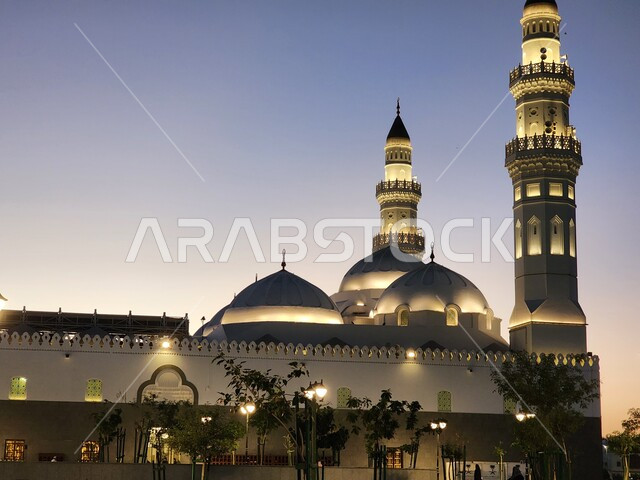 مسجد قباء في المدينة المنورة في وقت غروب الشمس، المآذن و القبب المضيئة، معالم وأماكن دينية مقدسة في المملكة العربية السعودية، دعوة المسلمين لآداء الصلاة والتقرب إلى الله تعالى، الفن الهندسي المعماري والديكورات الاسلامية على الطراز الحديث