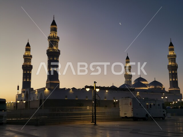 الساحة الخارجية لمسجد قباء في المدينة المنورة وقت الغروب، دعوة المسلمين لآداء الصلاة والتقرب إلى الله تعالى، معالم وأماكن دينية مقدسة في المملكة العربية السعودية، المآذن و القبب المضيئة، الفن الهندسي المعماري والديكورات الاسلامية على الطراز الحديث