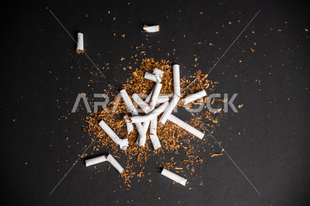 الادمان الضار على التدخين ، مجموعة من السجائر المتناثرة على لوح اسود   ، الادمان على التبغ ، ادمان السجائر ، تعاطي مواد ضارة و سامة ، عادات سلوكية ضارة ، لا للتدخين ، المواد ذات التأثير النفسي