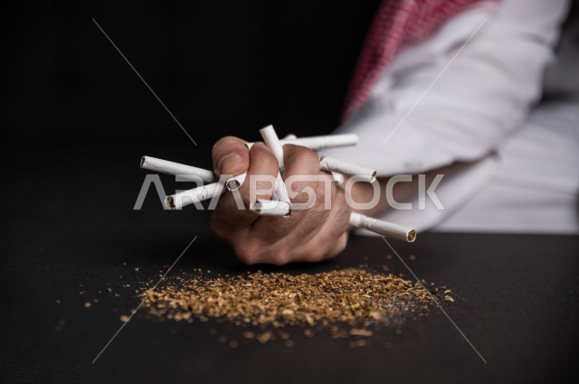 شاب عربي سعودي مدمن على التدخين ،  يمسك العديد من السجائر بيده  ، الادمان على التبغ ، ادمان السجائر ، تعاطي مواد ضارة و سامة ، عادات سلوكية ضارة ، لا للتدخين