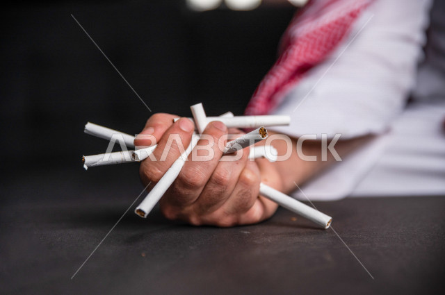 A young Saudi Arab who is addicted to smoking, holds many cigarettes in his hand, tobacco addiction, cigarette addiction, harmful and toxic substance abuse, harmful behavioral habits, no smoking
