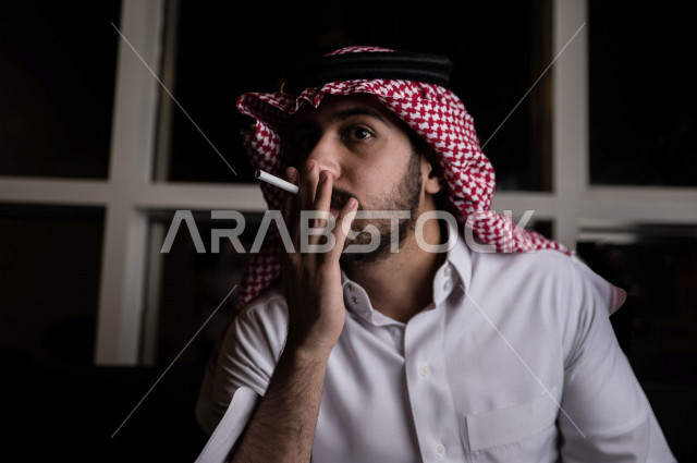 شاب عربي سعودي يقوم  بسحب نفساً عميقا من السيجارة ، الادمان على التبغ ، ادمان السجائر ، تعاطي مواد ضارة و سامة ، عادات سلوكية ضارة ، لا للتدخين