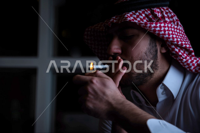 شاب عربي سعودي يقوم  بسحب نفساً عميقا من السيجارة ، الادمان على التبغ ، ادمان السجائر ، تعاطي مواد ضارة و سامة ، عادات سلوكية ضارة ، لا للتدخين