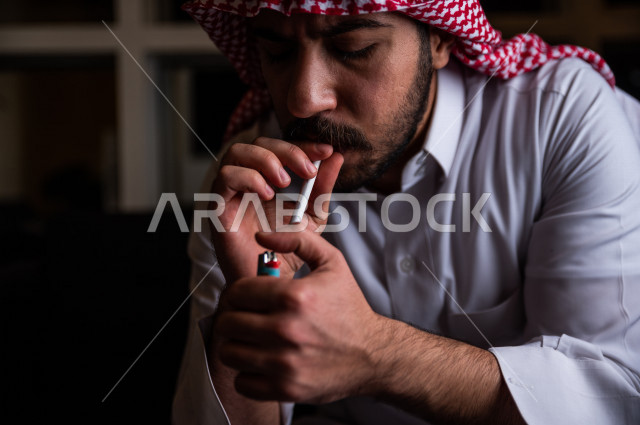شاب عربي سعودي يقوم  بسحب نفساً عميقا من السيجارة ، الادمان على التبغ ، ادمان السجائر ، تعاطي مواد ضارة و سامة ، عادات سلوكية ضارة ، لا للتدخين