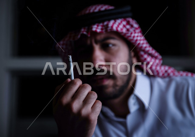 شاب عربي سعودي يقوم بتدخين السجائر ، الادمان على التبغ ، ادمان السجائر ، تعاطي مواد ضارة و سامة ، عادات سلوكية ضارة ، لا للتدخين