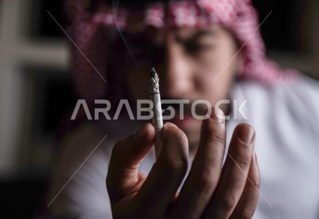 شاب عربي سعودي يقوم بتدخين السجائر ، الادمان على التبغ ، ادمان السجائر ، تعاطي مواد ضارة و سامة ، عادات سلوكية ضارة ، لا للتدخين