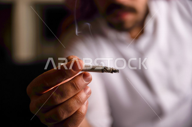 شاب عربي سعودي يقوم بتدخين السجائر ، الادمان على التبغ ، ادمان السجائر ، تعاطي مواد ضارة و سامة ، عادات سلوكية ضارة ، لا للتدخين
