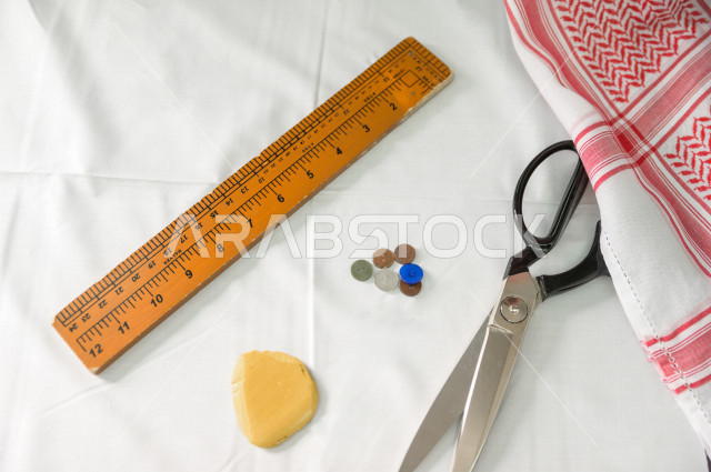 شاب سعودي خليجي يعمل في مهنة الخياطة ، يستخدم الأدوات المناسبة لتفصيل جلابية خاصة لاحدى الزبائن ، محل خياطة و تفصيل الملابس الرجالي في السعودية ، مهارة الخياطة واتقان تفصيل الملابس الشبابية