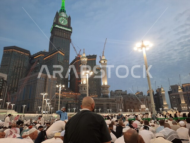 الحجاج والمعتمرين في الفناء الخارجي لبيت الله الحرام بانتظار اذان المغرب للإفطار, الفن الهندسي المعماري لبناء الأبراج والفنادق المحيطة بالمسجد, أداء العبادات والتقرب الى الله, معالم اسلامية مقدسة, الساحة الخارجية للحرم المكي في مكة المكرمة