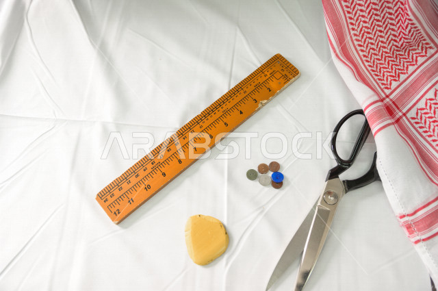 شاب سعودي خليجي يعمل في مهنة الخياطة ، يستخدم الأدوات المناسبة لتفصيل جلابية خاصة لاحدى الزبائن ، محل خياطة و تفصيل الملابس الرجالي في السعودية ، مهارة الخياطة واتقان تفصيل الملابس الشبابية