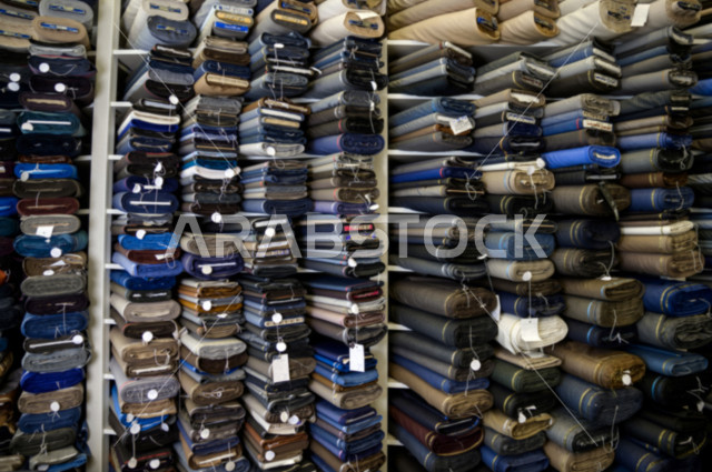 رفوف مليئة بمجموعة كبيرة من الأقمشة الملونة التي تستخدم لصناعة الملابس الرجالية ، محل خياطة و تفصيل الملابس الرجالي في السعودية ، مهارة الخياطة واتقان تفصيل الملابس الشبابية،