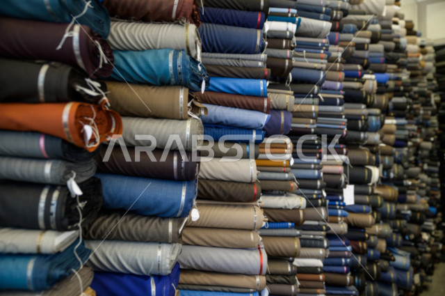 رفوف مليئة بمجموعة كبيرة من الأقمشة الملونة التي تستخدم لصناعة الملابس الرجالية ، محل خياطة و تفصيل الملابس الرجالي في السعودية ، مهارة الخياطة واتقان تفصيل الملابس الشبابية،