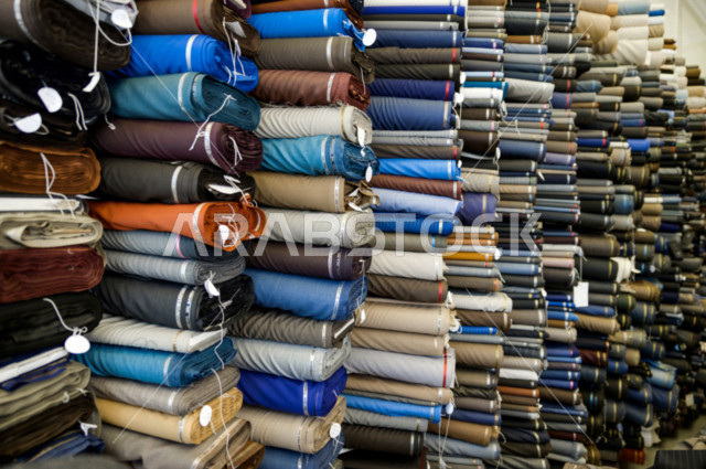 شاب سعودي خليجي يعمل في مهنة الخياطة ، يعرض للزبون اجود انواع الأقنشة لتفصيل الثوب السعودي ، محل خياطة و تفصيل الملابس الرجالي في السعودية ، مهارة الخياطة واتقان تفصيل الملابس الشبابية