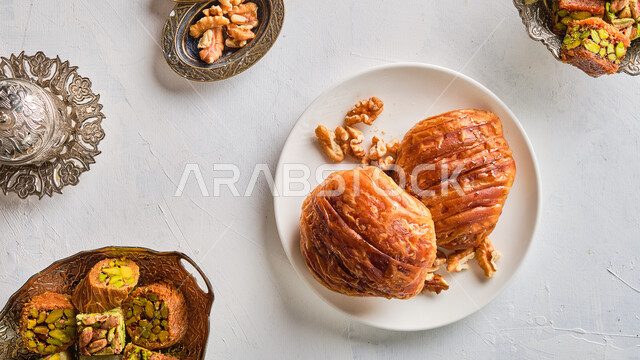 Saudi desserts with pistachios and nuts, dishes of oriental Arab sweets, foods rich in sugars and calories, popular pieces stuffed with walnuts and delicious cream, national local products, warm hospitality in Gulf society.