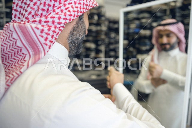 A young Saudi Gulf man inside a shop specializing in detailing men's clothes, measuring his dishdasha, a men's tailoring and tailoring shop in Saudi Arabia, sewing skill and mastering the tailoring of youthful clothes