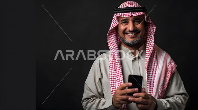 Gestures of happiness and joy, looking at the camera with expressions of pleasure, a close-up portrait of a smiling Saudi Gulf Arab man wearing a shemagh and traditional thobe, holding a mobile phone in his hand, using advanced modern technology and technical devices, black background