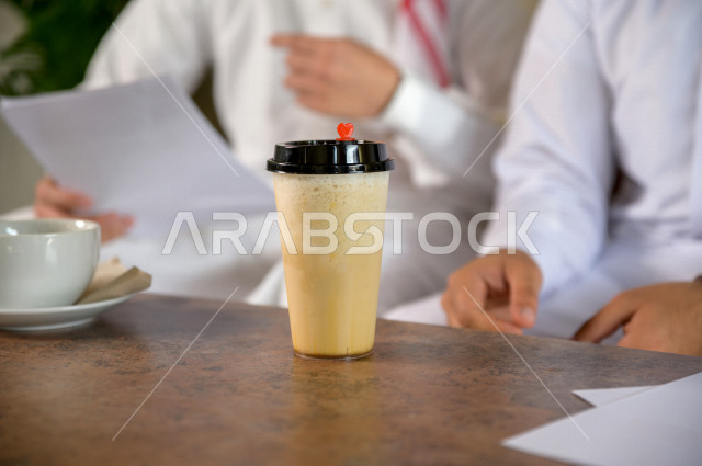 two Saudi men drinking coffee in a cafe , a hot cup of coffee 