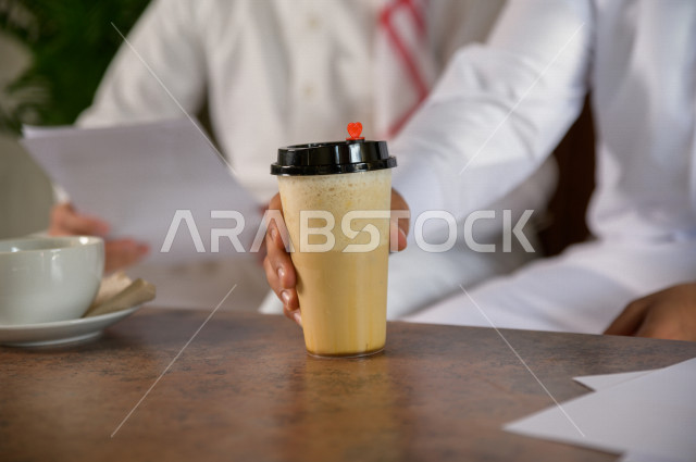 two Saudi men drinking coffee in a cafe , a hot cup of coffee 