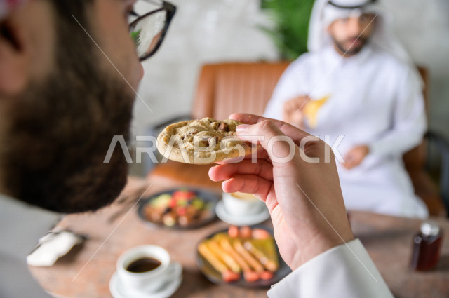   , Saudi business partners are enjoying an assortment of desserts and coffee at a cafe , enjoying a peaceful environment at a local cafe  