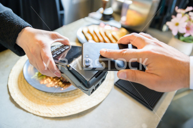 شخص يدفع الحساب بواسطة الهاتف الذكي في المقهى , استخدام نقاط البيع للدفع , سهولة الدفع الآلي 