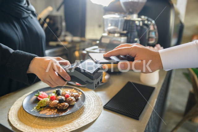 شخص يدفع الحساب بواسطة الهاتف الذكي في المقهى , استخدام نقاط البيع للدفع , سهولة الدفع الآلي 