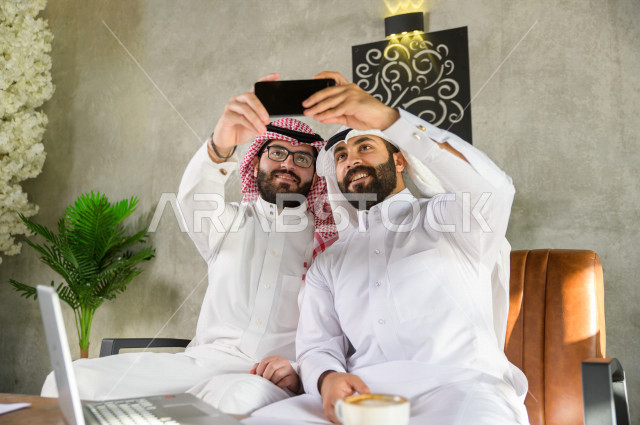 شابان سعوديان خليجيان يقضيان أوقات ممتعة في المقهى , التقاط صور سلفي تذكاريه باستخدام الهاتف المحمول , اجتماع شبابي في كافيه 