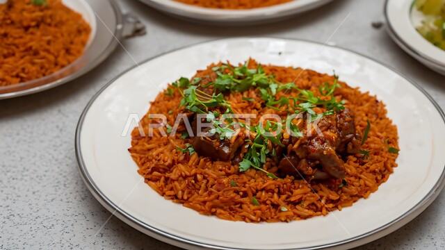 A plate of saffron rice with pieces of cooked meat, the arts of catering in oriental restaurants, basic traditional Arabic foods and dishes in Saudi holidays, a close-up of a machboos dish, and delicious food recipes