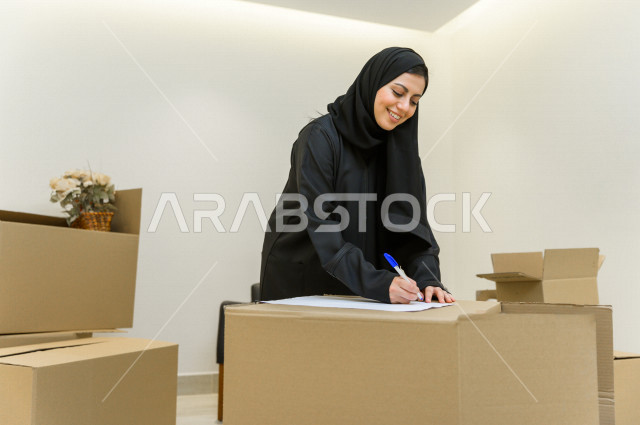 مرأه عربية سعودية داخل منزلها الجديد ، تصمم ورقة مخطط المنزل  ،امتلاك بيت جديد ،ايماءات وجه و يدين تدل على السعادة والانسجام ، الترتيب و التنظيم ، النقل و التوصيل 