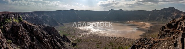 The reflection of the sun on the water of the lake at the bottom of the Al-Waabah Crater, mountains and natural rocky heights, historical archaeological landmarks, tourist places in Saudi Arabia, (the bottom of the caldera) in an alluvial quarry in the city of Taif in the Kingdom