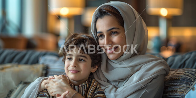 مفهوم الأمومة و قضاء وقت ممتع مع الأبناء، صورة مقربة لإمرأة عربية خليجية اماراتية تقوم باحتضان ابنها، اجواء عائلية سعيدة، ايماءات السعادة والسرور، الشعور بالحب والحنان الأسري