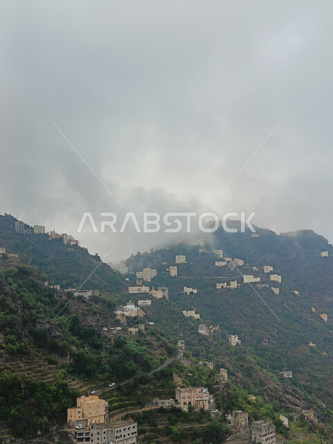  الأشجار والنباتات الخضراء المزروعة على سفوح الجبال, الاستمتاع بالمناظر الطبيعية في الأماكن السياحية في المملكة العربية السعودية، الغيوم والأجواء الضبابية فوق القمم والمرتفعات الجبلية في محافظة فيفاء، المدرجات الزراعية والبيوت والمباني السكنية في مدينة جازان