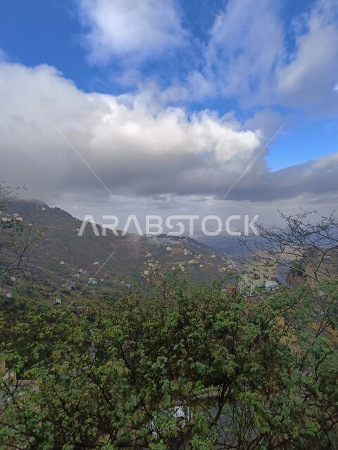  الأشجار والنباتات الخضراء المزروعة على سفوح الجبال, الاستمتاع بالمناظر الطبيعية في الأماكن السياحية في المملكة العربية السعودية، الغيوم والأجواء الضبابية فوق القمم والمرتفعات الجبلية في محافظة فيفاء، المدرجات الزراعية والبيوت والمباني السكنية في مدينة جازان