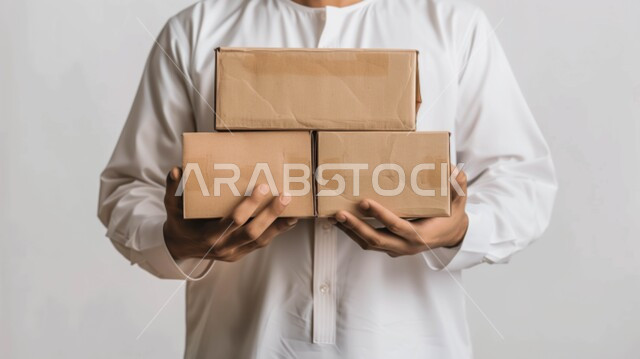 خدمات التوصيل السريع، عمليات الشحن الموثوقه, بورتريه مقرب لمندوب عربي سعودي خليجي يحمل بيده صناديق كرتونية، العمل في توصيل الطلبات والبضائع للزبائن والعملاء, التسوق الالكتروني الآمن, استلام طلبات الاونلاين, خلفيه بيضاء