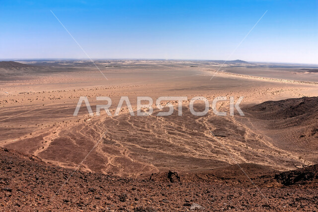 Dormant volcanic fields, Harrat Kashab field in the holy city of Mecca during the day, attractions for geotourism in the Kingdom of Saudi Arabia, desert environment and golden sand in front of volcanoes